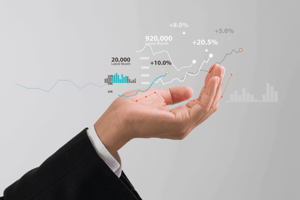 A hand holding up digital charts and graphs representing financial growth and statistics