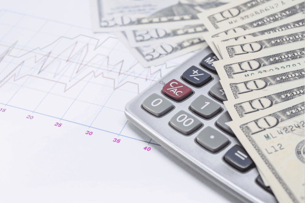 Calculator and US dollar bills on top of financial graph