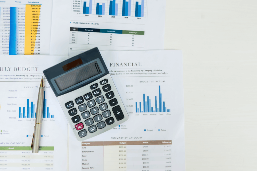 Calculator and pen placed on financial reports with bar charts