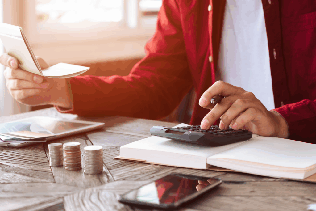 Person calculating finances with coins calculator and passbook on desk