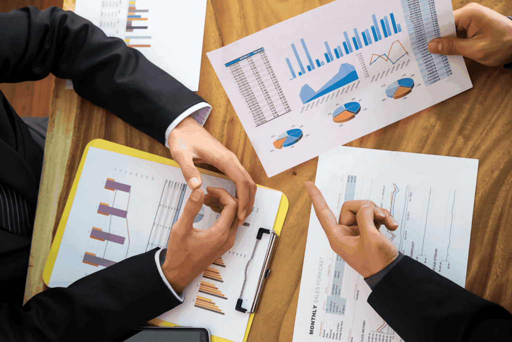 Close-up of hands analyzing printed sales reports with bar and pie charts during