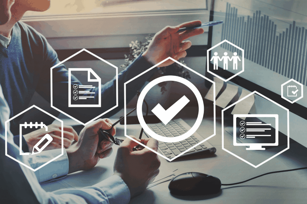 Hands pointing at charts on a screen with an overlay of digital compliance icons.
