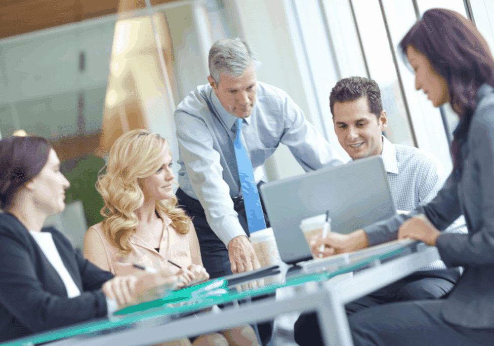 Business team gathered around a laptop in a modern office meeting