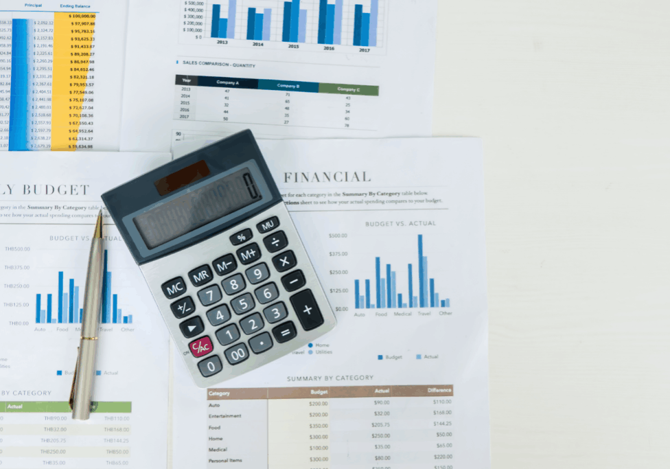 Calculator and pen placed on financial reports with bar charts