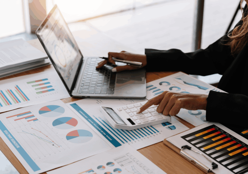 Person analyzing charts with calculator and laptop