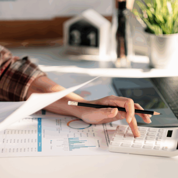 Person analyzing financial charts with a calculator and laptop on desk