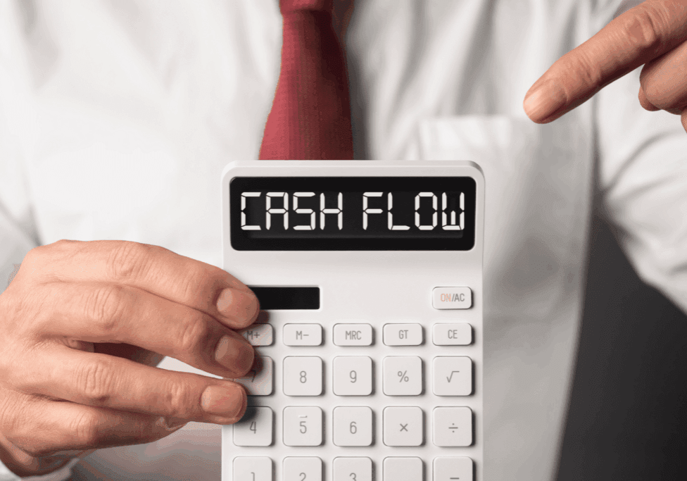 Man in a shirt and tie pointing to a calculator displaying the words “CASH FLOW.”