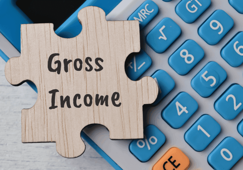 Wooden puzzle piece labeled Gross Income on a blue calculator