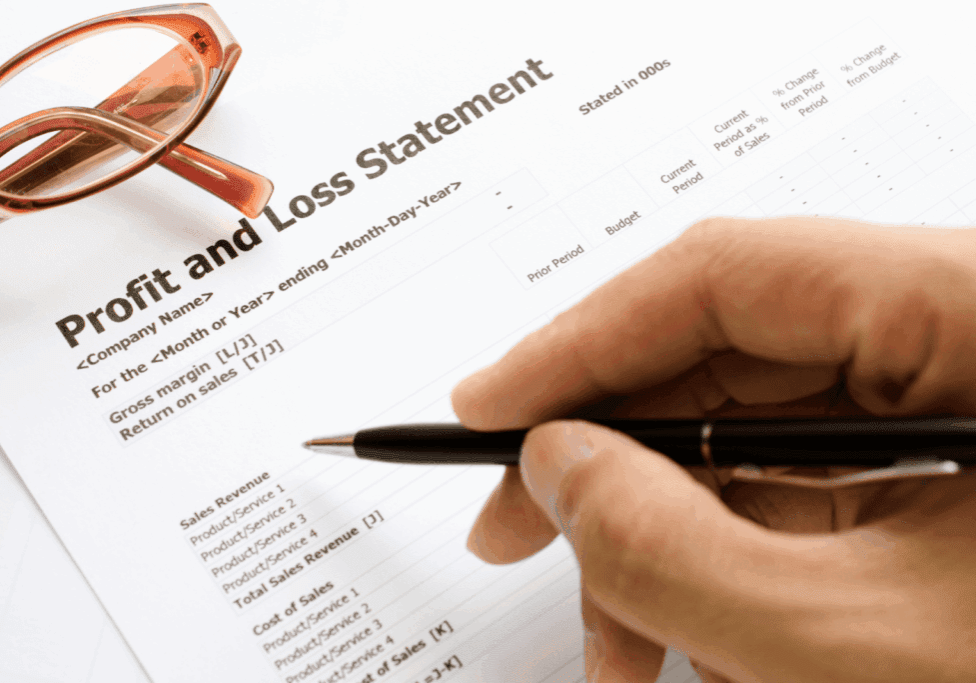 Balance sheet document with financial figures and a black-and-gold pen on top.