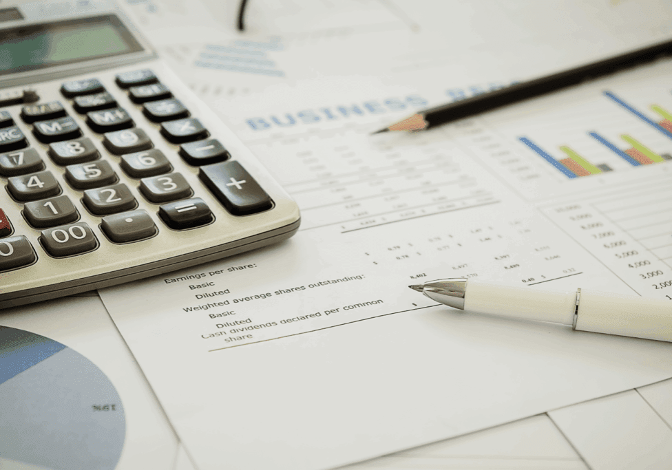 A close-up of business documents, charts, and a calculator on a table