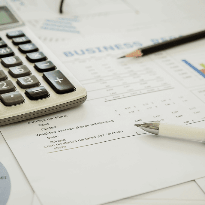 A close-up of business documents, charts, and a calculator on a table